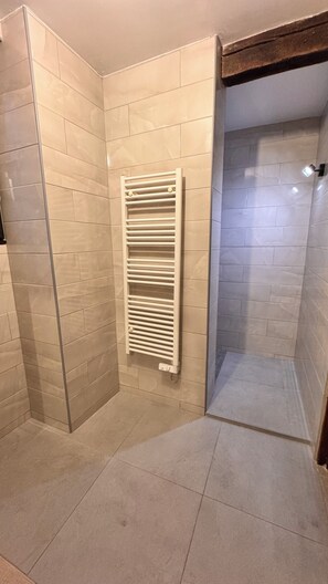 A shower with a glass door, beige tiled walls, and a white towel rack. - Charming, quiet house, fully equipped for a family or professional getaway! (Casseneuil)