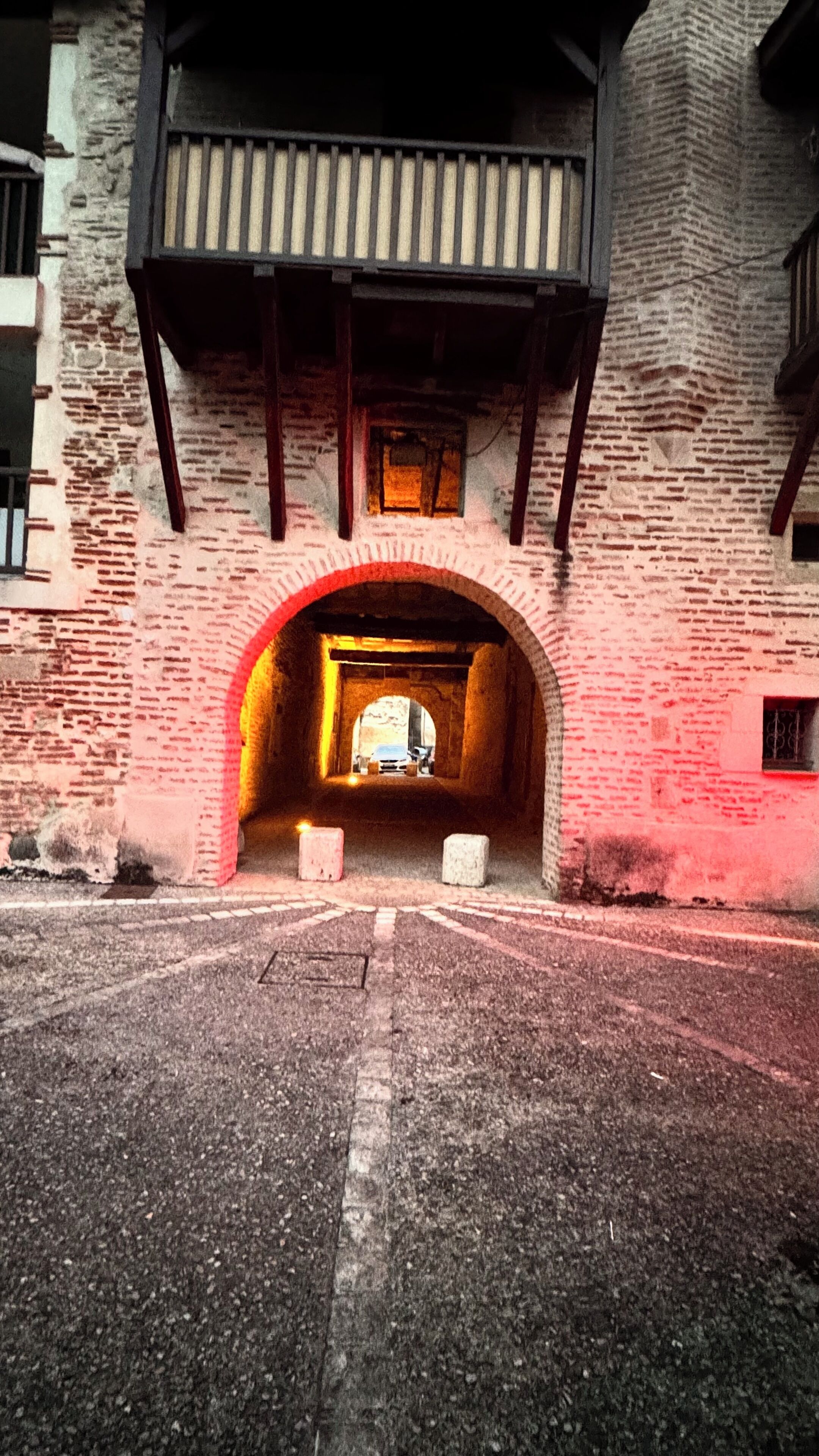 A tunnel entrance with brick walls and a wooden balcony above.