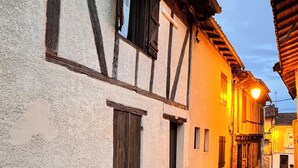 A narrow street with traditional half-timbered buildings, a clear sky, and a manhole cover on the pavement. - Charming, quiet house, fully equipped for a family or professional getaway! (Casseneuil)