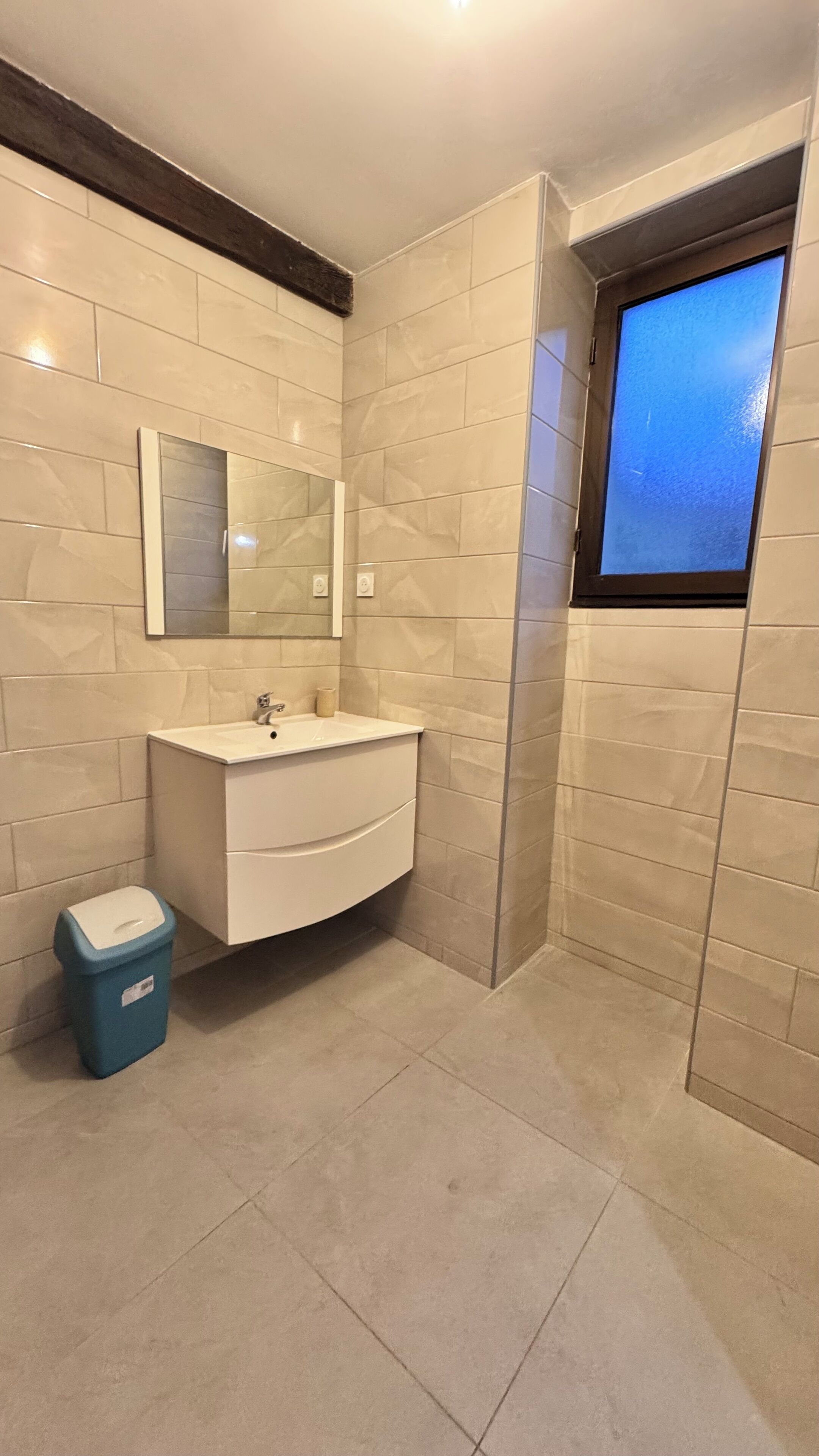 Une salle de bain moderne avec un meuble-lavabo blanc, un miroir et une fenêtre.