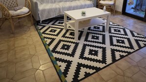 A living room with a sofa, two chairs, a coffee table, a patterned rug, and a ceiling with exposed beams. - Charming, quiet house, fully equipped for a family or professional getaway! (Casseneuil)