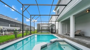A swimming pool with a glass enclosure, surrounded by a patio area with lounge chairs. - Luxury Oasis Near Disney 6Brds ,with Private Pool (Clermont)