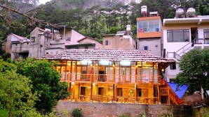 A two-story wooden building with a tiled roof, surrounded by greenery and other buildings. - Chai Eco House Mu Cang Chai (Mu Cang Chai)