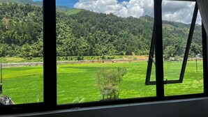 A view through a window of a green field and forested hills. - Chai Eco House Mu Cang Chai (Mu Cang Chai)