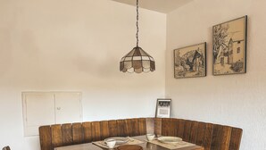 A dining area with a wooden table, chairs, and a hanging light fixture. - Gemütliche individuelle Wohnung oberhalb der Oker-Talsperre. (Schulenberg im Oberharz)