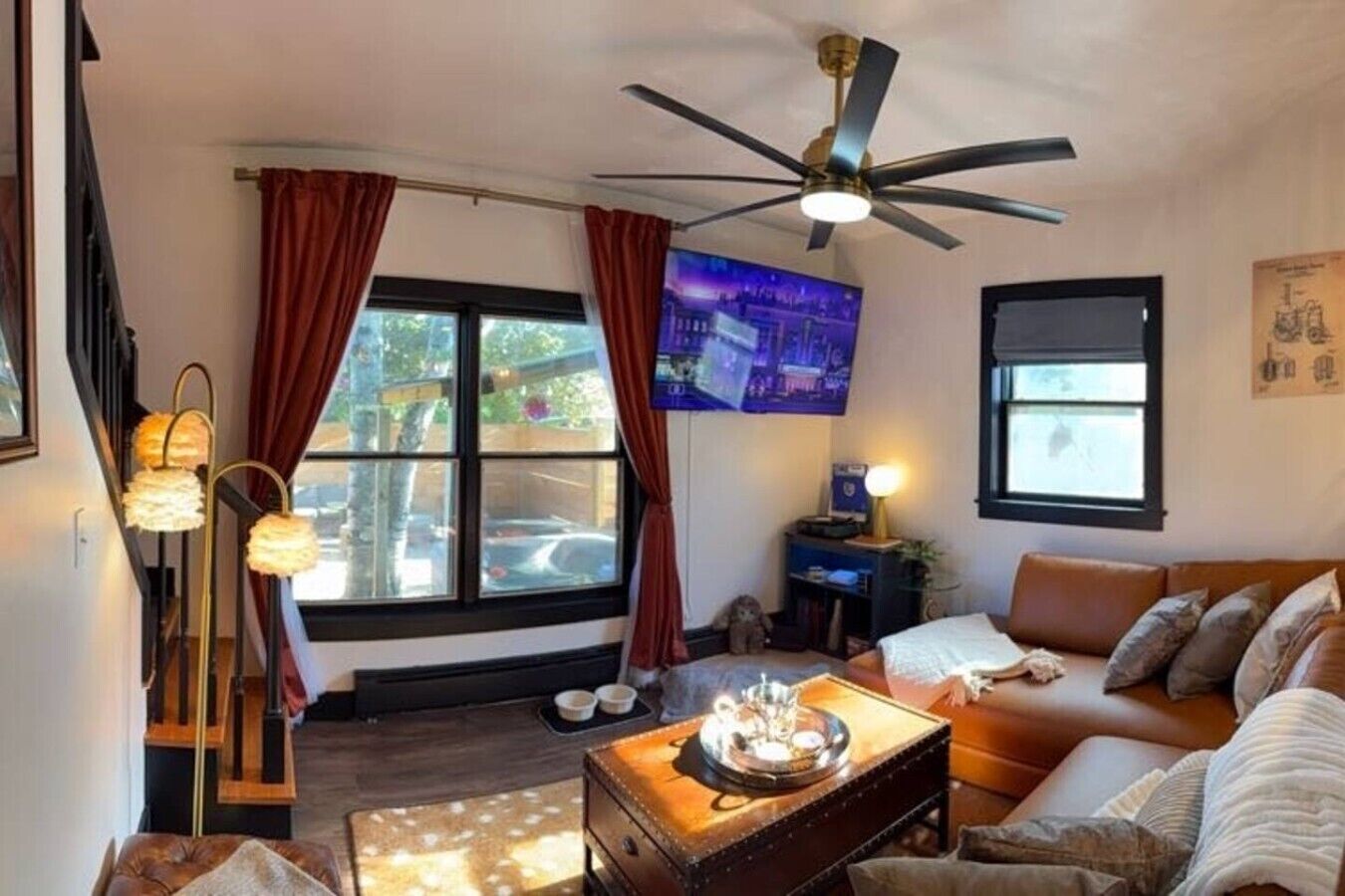 A cozy living room with a sofa, a coffee table, a TV, and a ceiling fan.