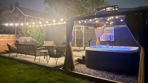 An outdoor patio with a hot tub, string lights, and outdoor furniture.