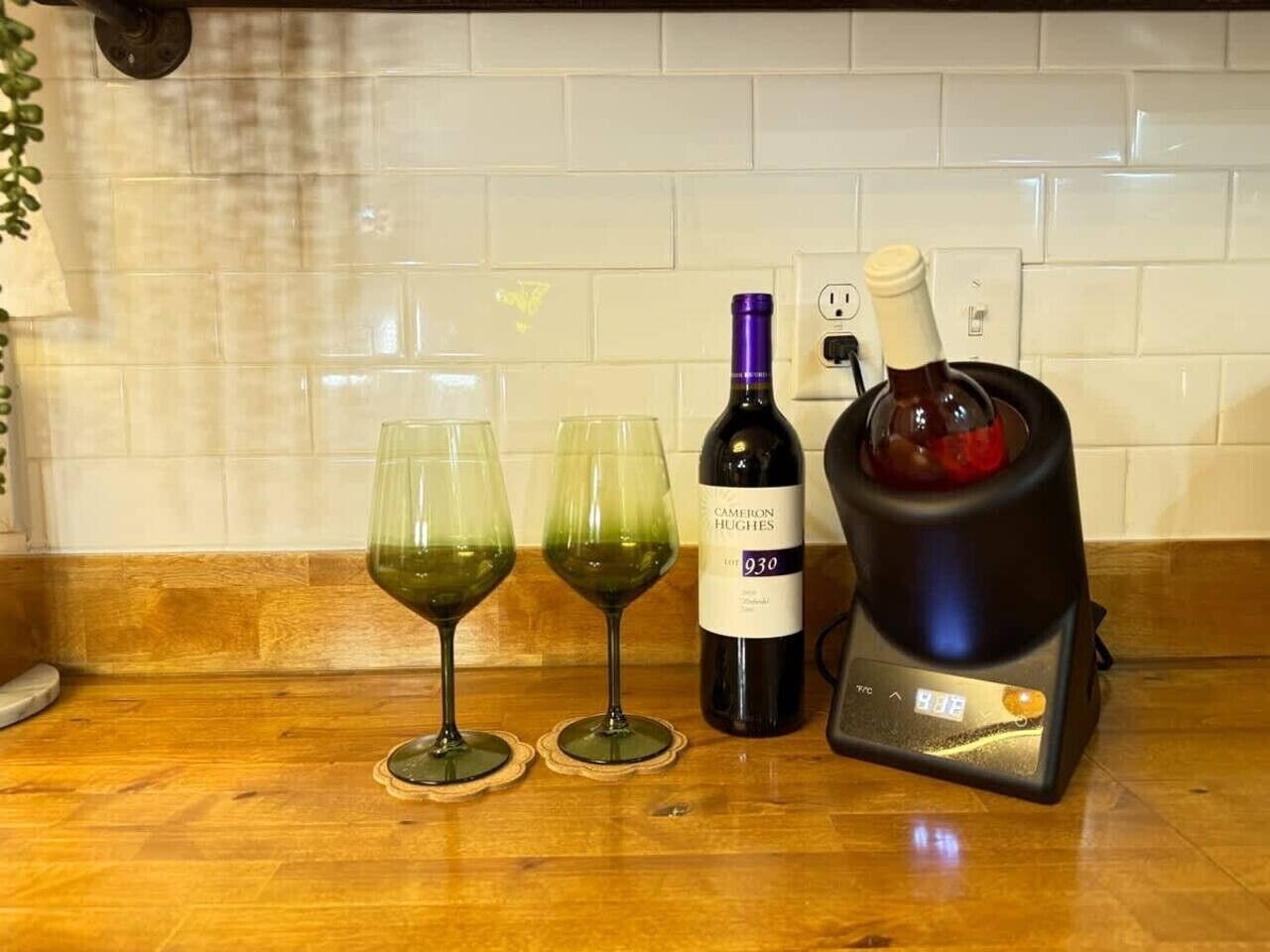 Una encimera de cocina con dos copas de vino, una botella y un refrigerador para vino.