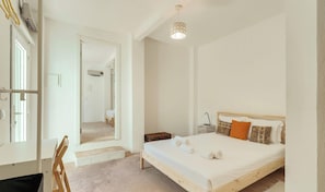 A bedroom with a bed, bedside table, lamp, and a view of a hallway.