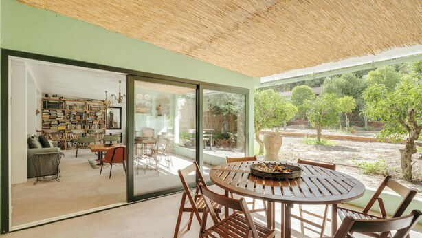 Un interior moderno con comedor, estantería y vistas al exterior.