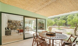 Um interior moderno com área de jantar, estante de livros e vista para o exterior.