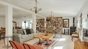 Un salón espacioso con una amplia estantería, una mesa de centro de madera y una chimenea.