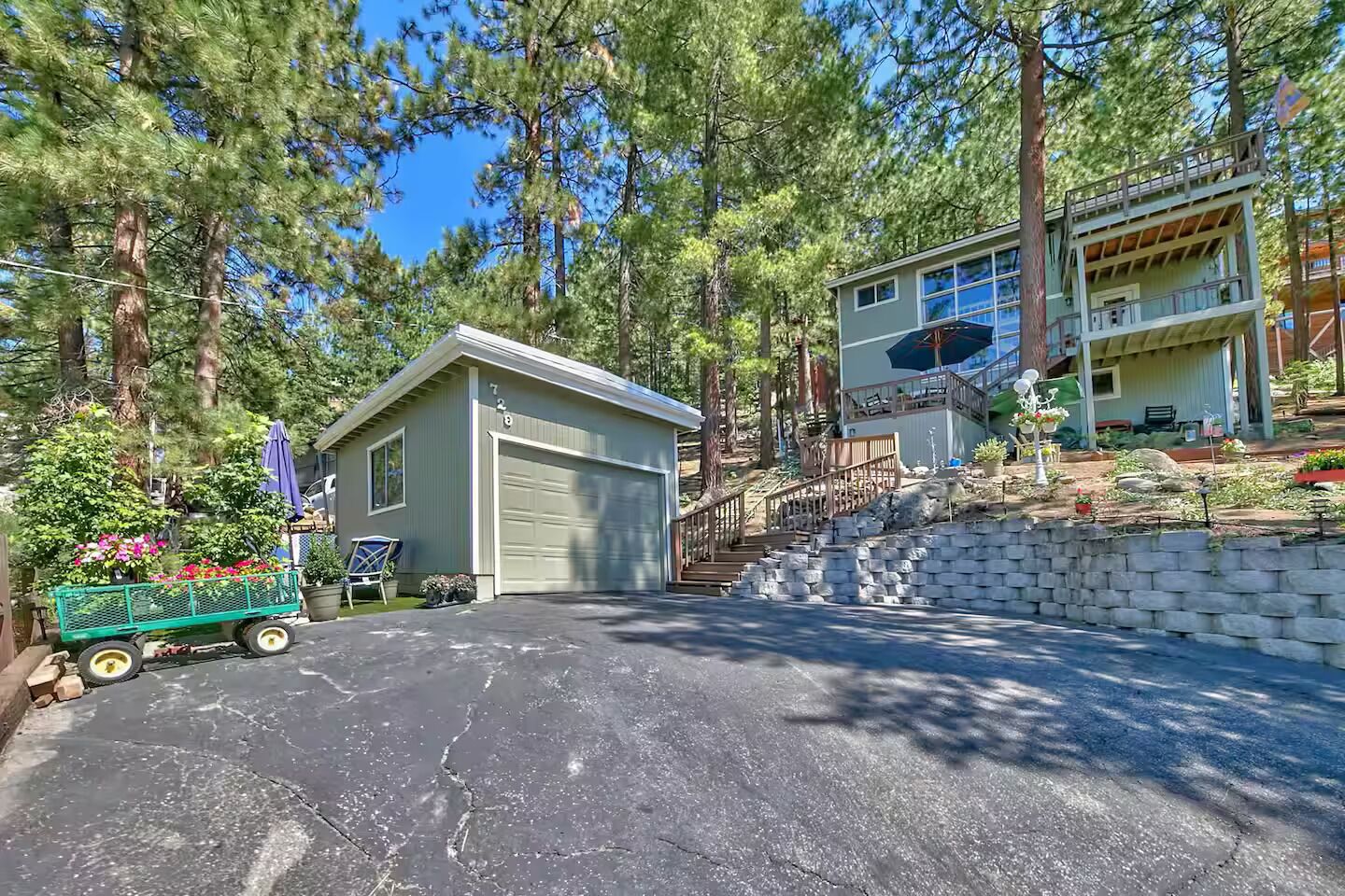 Un bâtiment à deux étages avec un garage, entouré d’arbres.