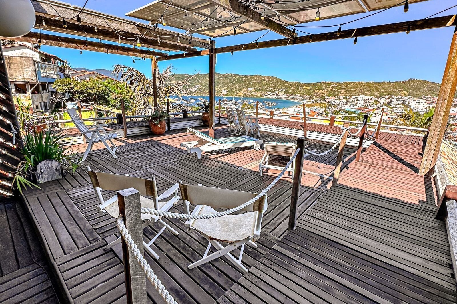 A wooden deck with outdoor seating, overlooking a coastal town and harbor.