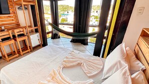 A hotel room with a bed, a hammock, and a view of the outside. - Villa Rustica (Arraial do Cabo)