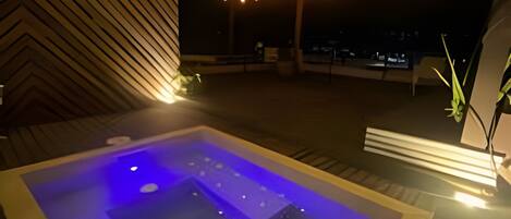 Ein Whirlpool mit blauer Beleuchtung, Holzboden und Lichterkette.