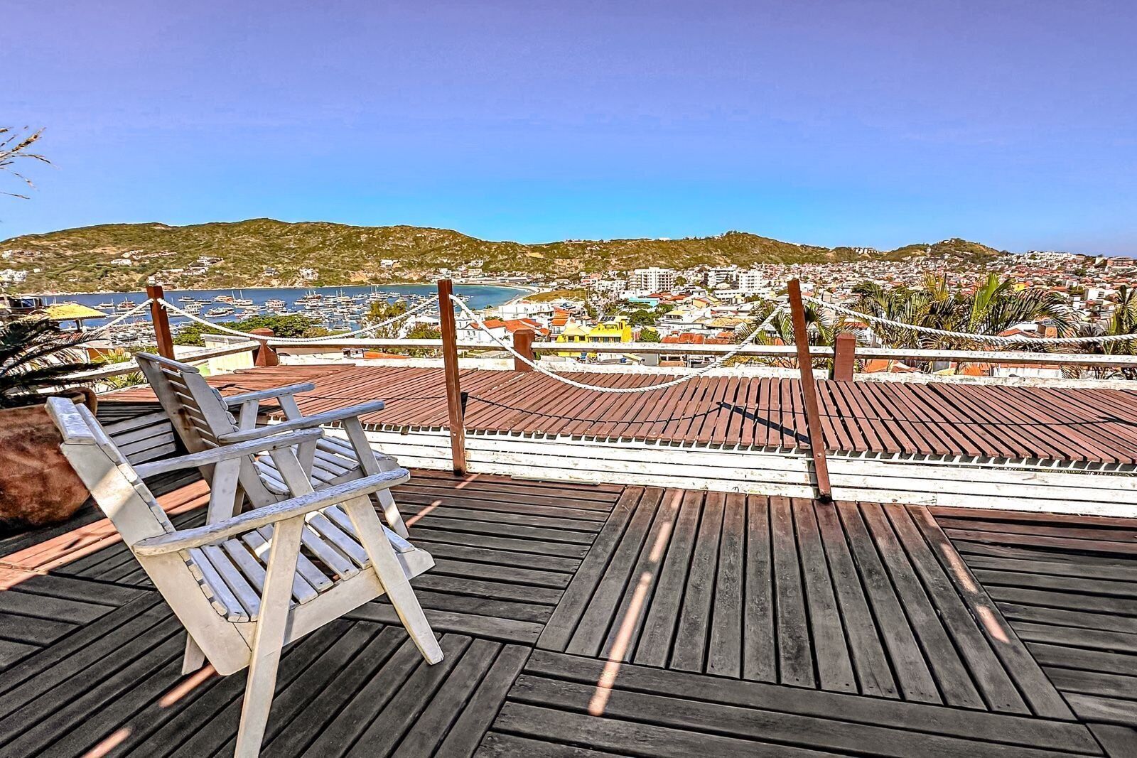 A wooden deck with chairs overlooking a coastal town.