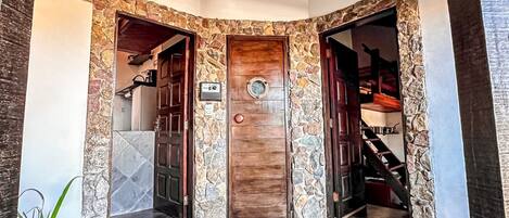 A stone-framed entrance with two doors, a doormat, and a tiled floor.