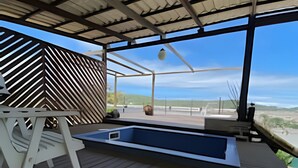 A covered outdoor area with a hot tub, wooden deck, and a view of the ocean. - Villa Rustica (Arraial do Cabo)