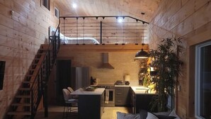 Tunnelmallinen mökin sisustus, jossa on puupanelointi, portaat, ruokailutila ja sohva.
