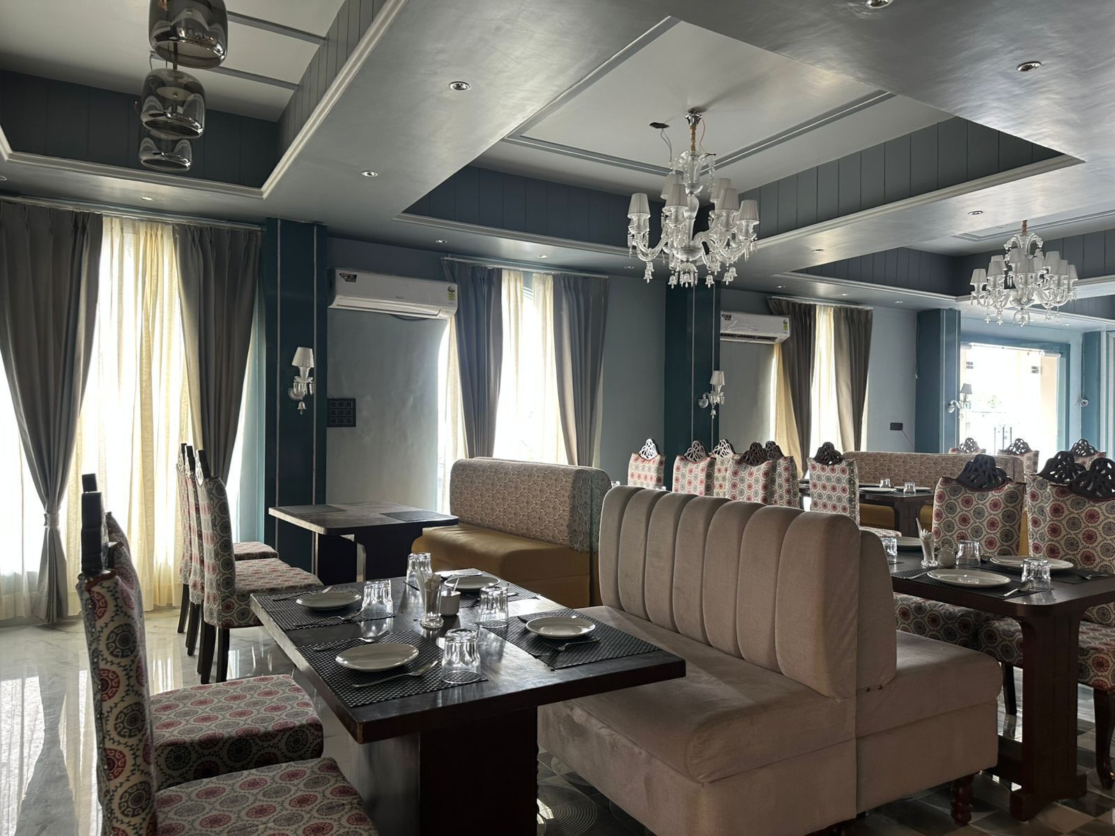 A dining area with a long table set for six, surrounded by patterned chairs.
