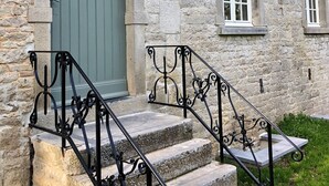 A stone building with a green door, white-framed windows, and a metal staircase with intricate balusters. - Historic Gardener's House in Haltinne (Gesves)