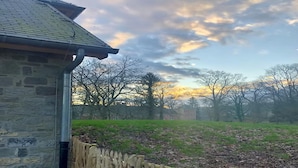 A stone building with a wooden fence and a grassy field in the background. - Historic Gardener's House in Haltinne (Gesves)