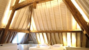 A bedroom with a large skylight, a bathtub, and a bed with white linens. - Historic Gardener's House in Haltinne (Gesves)