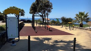 An outdoor fitness area with exercise equipment, a sign with instructions, and a view of the sea. - Villa Gabriella "Sea View" (Upper Floor Apartment) (Santa Maria del Mare)