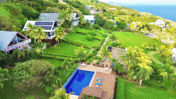 Un quartier résidentiel comprenant plusieurs maisons, une piscine et une vue sur la mer.