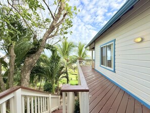 Une maison avec une terrasse en bois, une balustrade blanche et des bordures bleues.