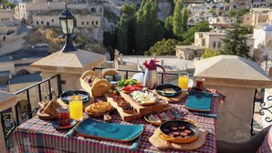 A table set with a variety of foods and drinks on a balcony overlooking a cityscape. - Castle Inn Cave Cappadocia (Nevşehir)