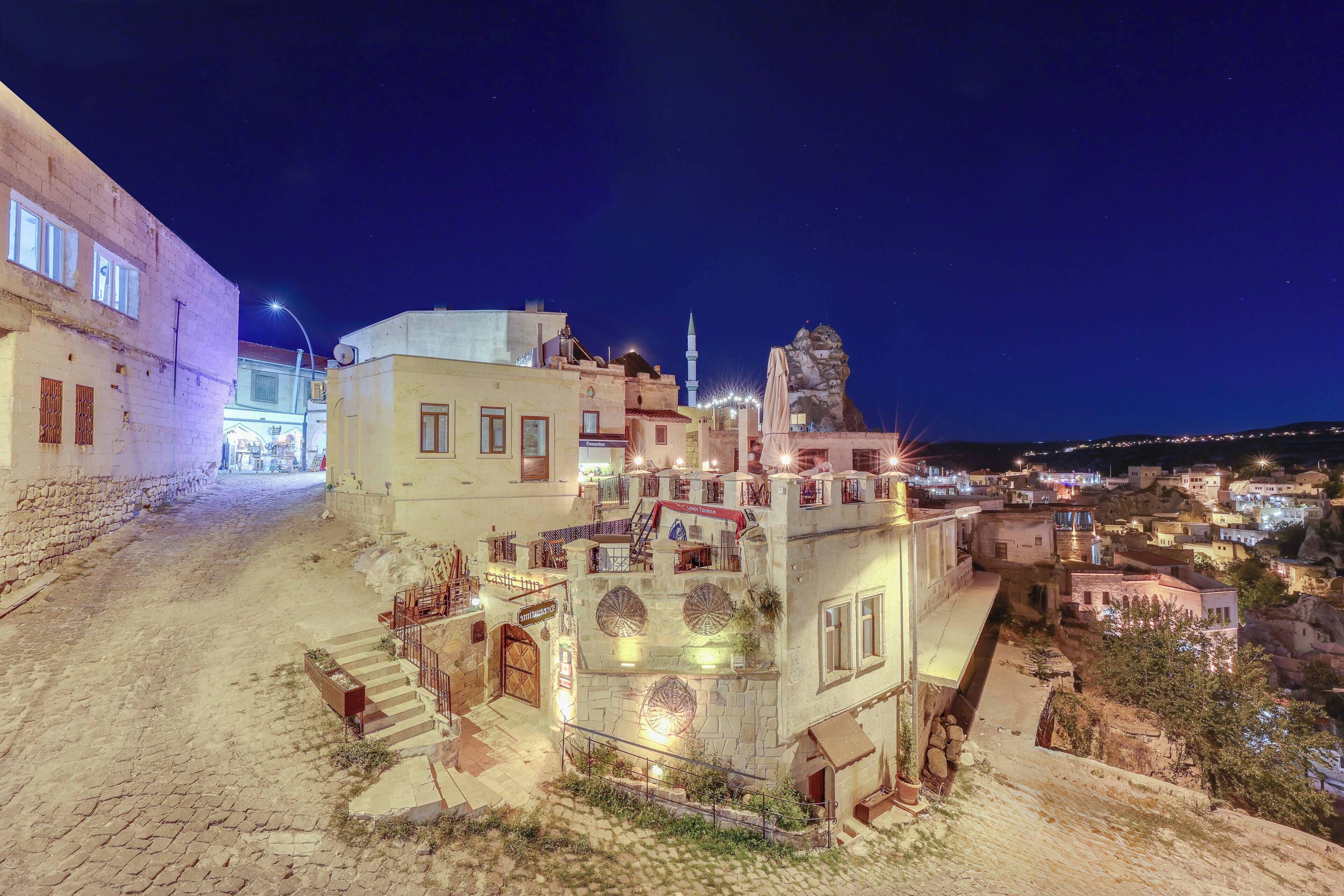 A historic building with a prominent minaret, a cobblestone street, and a view of the surrounding town at night.