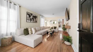 Ein Wohnzimmer mit einem Ecksofa, einem Couchtisch und einem Fernseher an der Wand.