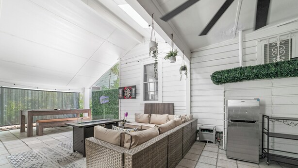 Eine geräumige Terrasse mit Korbusofa, Esstisch und hängenden Pflanzen.