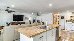 Uma cozinha moderna com bancada de madeira, armários brancos e lava-louças embutida.