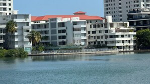 Ein Hotel am Wasser mit mehreren Etagen, Balkonen und einem roten Dach.