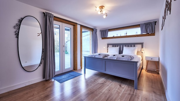 Un dormitorio con cama, un espejo grande y una ventana con cortinas.