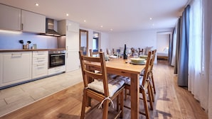 Una cocina moderna con armarios blancos, una mesa de comedor de madera y sillas.