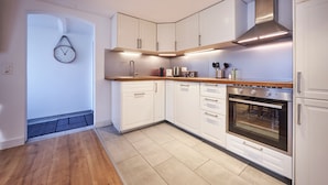 Una cocina moderna con armarios blancos, horno de acero inoxidable y encimera de madera.