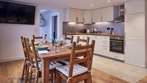 Una cocina moderna con armarios de madera, horno empotrado y una mesa de comedor lista para seis comensales.