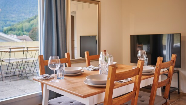 A dining table set with plates, glasses, and cutlery, with chairs around it.