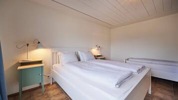 A bedroom with two beds, a nightstand with a lamp, and a wall-mounted light fixture.