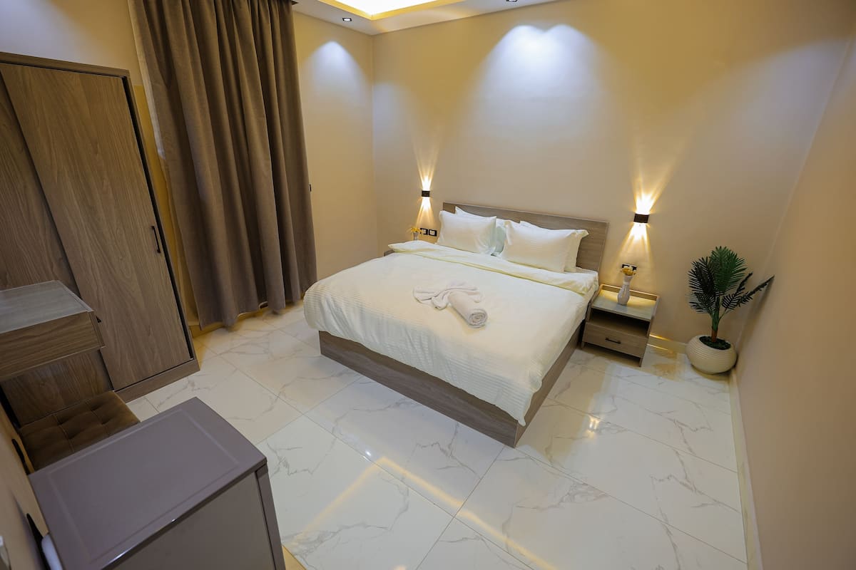 Une chambre d’hôtel avec un grand lit, une armoire en bois et un petit bureau.