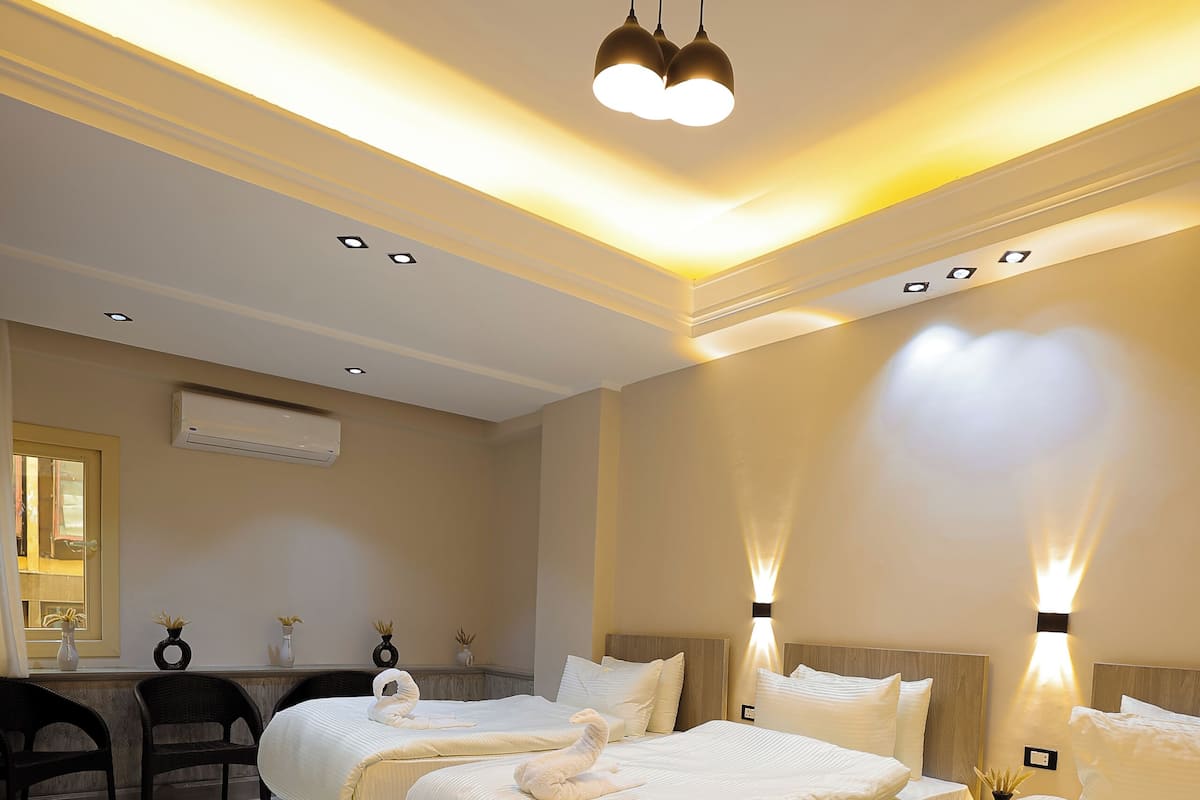 Une chambre d’hôtel avec deux lits, un bureau et un miroir.
