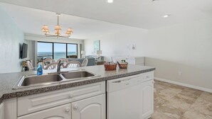 A kitchen with a granite countertop, white cabinetry, a built-in dishwasher, and a ceiling light fixture. - Gulf-Front Condo - Heated Pool - Sunset Views - Direct Beach Access - Sleeps 5 (Indian Shores)