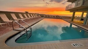 A swimming pool with a sunset view, lounge chairs, and a lifeguard stand. - Gulf-Front Condo - Heated Pool - Sunset Views - Direct Beach Access - Sleeps 5 (Indian Shores)