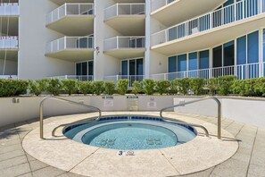 A swimming pool with a 3ft depth marker, surrounded by a pool deck, and a building with balconies in the background.