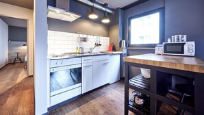 Une cuisine moderne avec des armoires blanches, un four encastré et un micro-ondes posé sur le plan de travail.