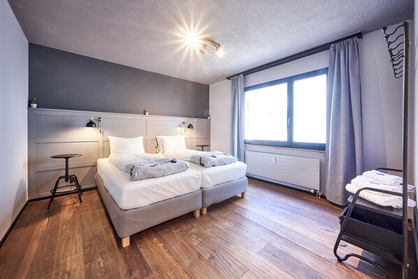 Une chambre moderne avec un lit, des tables de chevet, une fenêtre avec des rideaux et un radiateur.